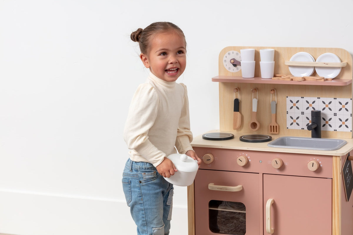 Three-year-old cooking at the OmaOmaOma wooden play kitchen — toddler-scale pretend kitchen in FSC-certified wood